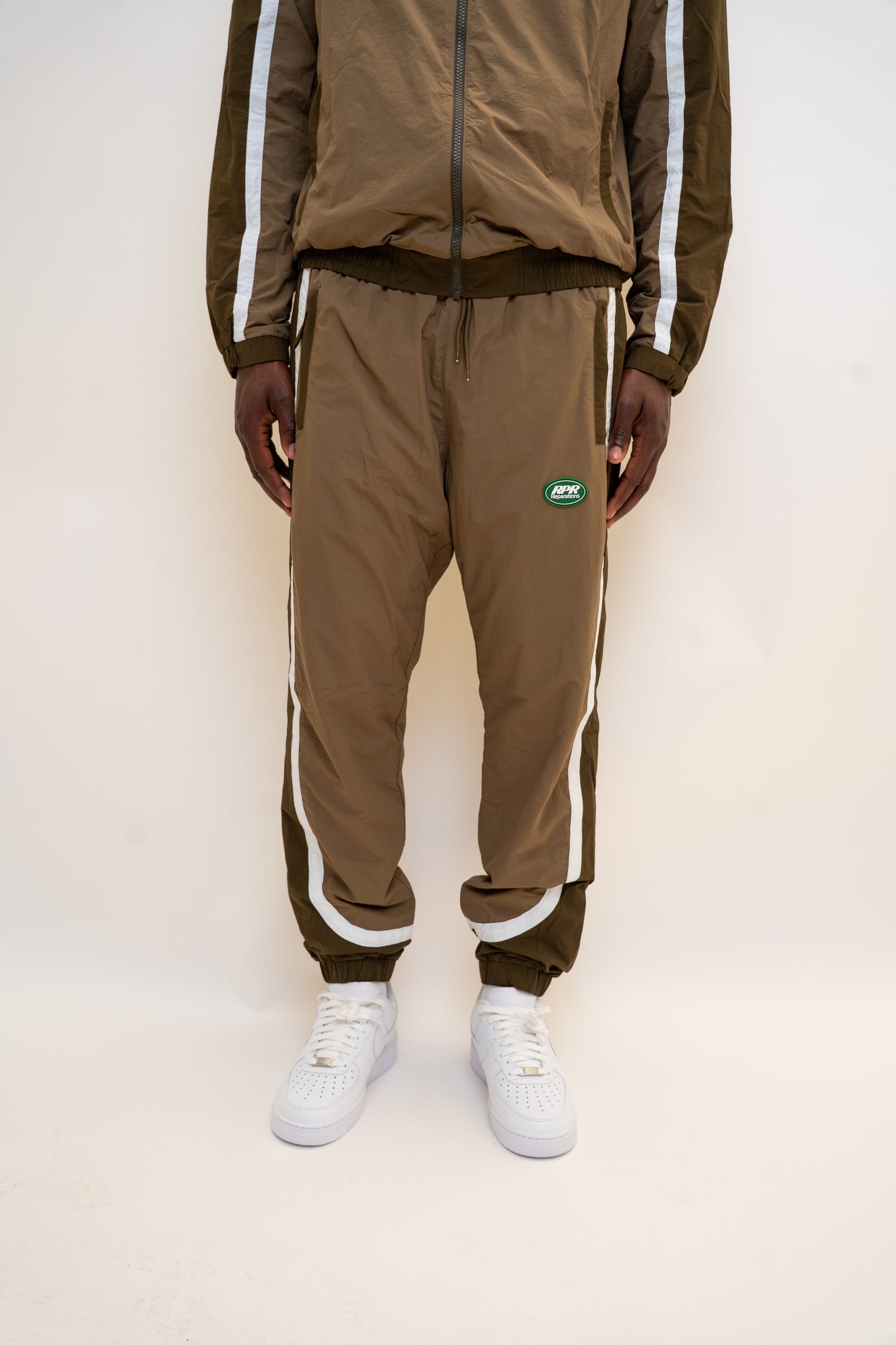 khaki tracksuit
brown nylon tracksuit
RPR DopeBoy set
military green tracksuit
unisex two-piece activewear
full zip tracksuit with logo
lightweight streetwear set
mesh-lined tracksuit
nylon jacket and pants set
urban utility style tracksuit